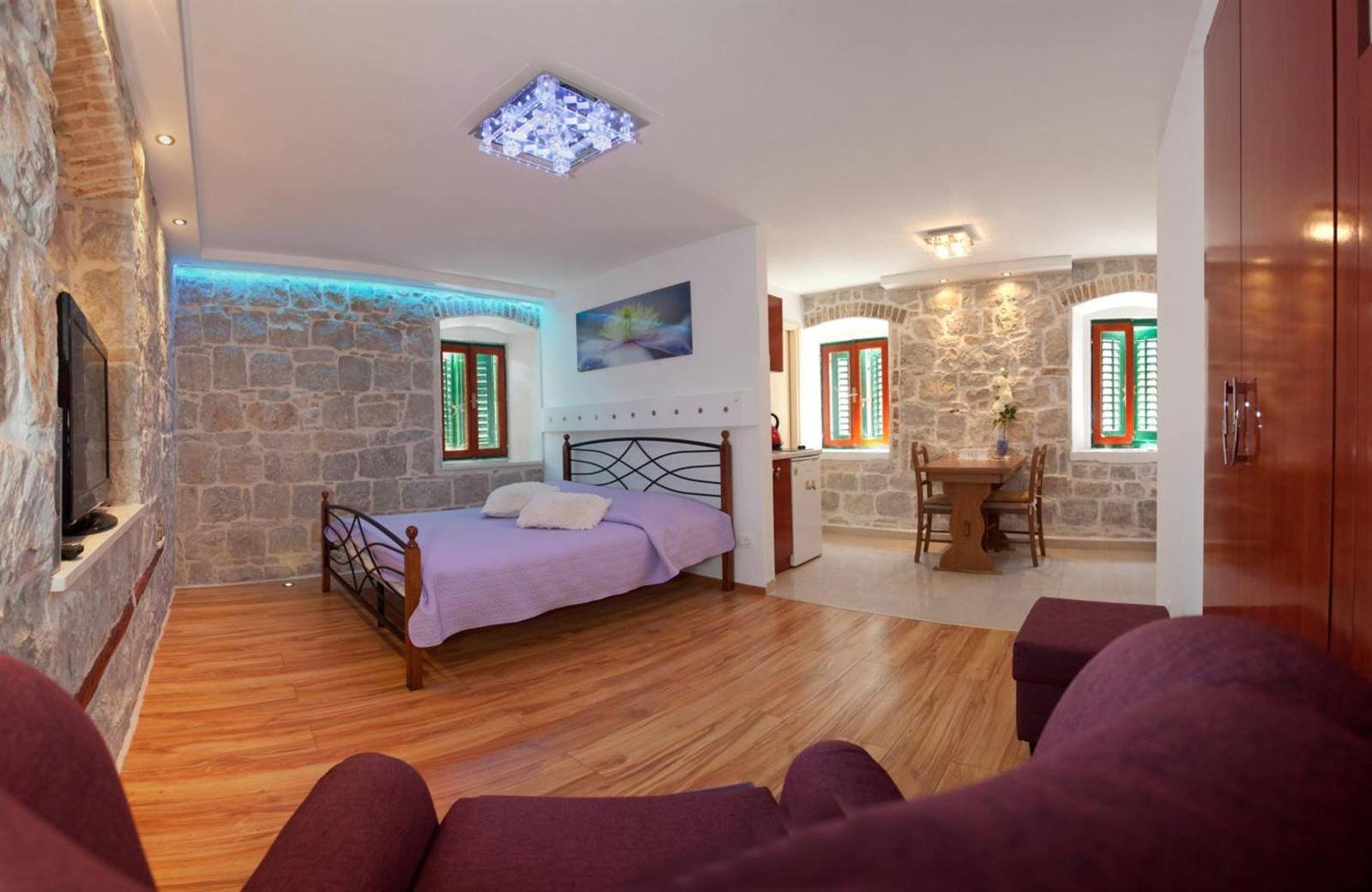 Room with stone walls, a wooden floor, a sofa and a small dining table