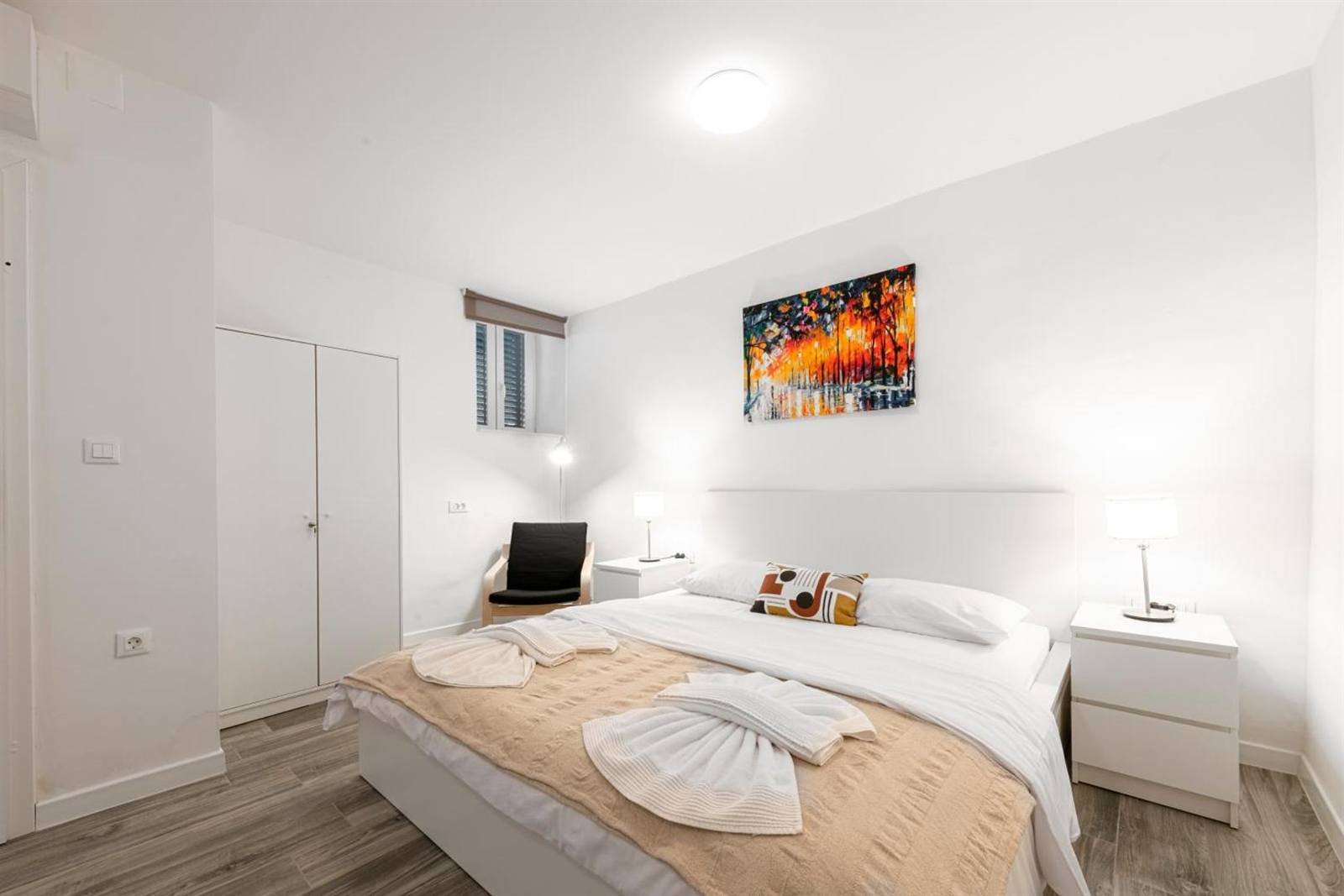 Bright white room with a double bed and a bathrobe
